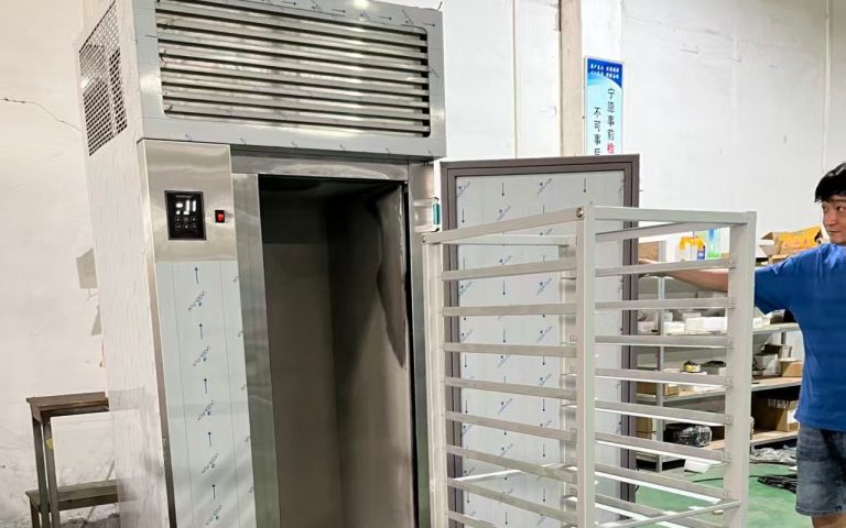 Stainless steel blast freezer unit with a pulled-out rack trolley in a food processing factory